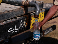 A paramilitary soldier fills water in a bottle as Kashmiri polling officials carry sealed Electronic Voting Machines (EVM) and Voter Verifia...