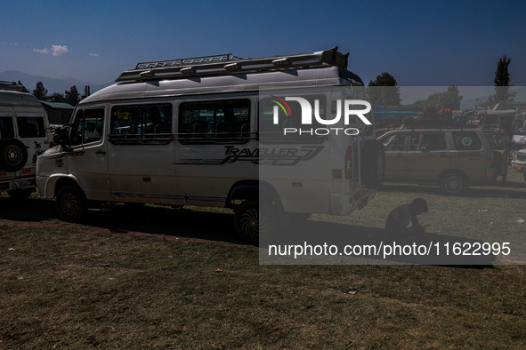 A driver rests behind a van as Kashmiri polling officials carry sealed Electronic Voting Machines (EVM) and Voter Verifiable Paper Audit Tra...