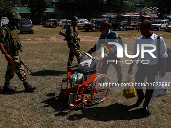 Kashmiri polling officials carry sealed Electronic Voting Machines (EVM) and Voter Verifiable Paper Audit Trail (VVPAT) machines as they mov...