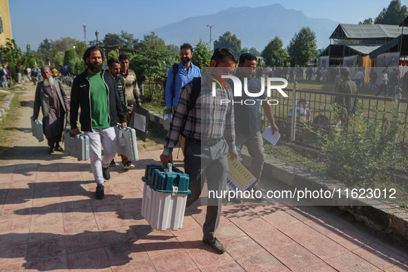 Polling officials carry electronic voting machines (EVM) at a distribution center in Sumbal area of Bandipora district, North of Srinagar, o...