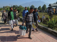 Polling officials carry electronic voting machines (EVM) at a distribution center in Sumbal area of Bandipora district, North of Srinagar, o...