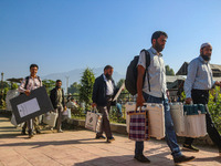 Polling officials carry electronic voting machines (EVM) at a distribution center in Sumbal area of Bandipora district, North of Srinagar, o...