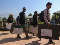 Polling officials carry electronic voting machines (EVM) at a distribution center in Sumbal area of Bandipora district, North of Srinagar, o...