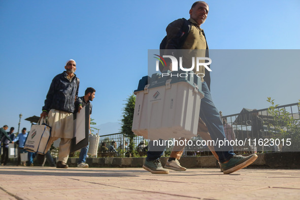 Polling officials carry electronic voting machines (EVM) at a distribution center in Sumbal area of Bandipora district, North of Srinagar, o...