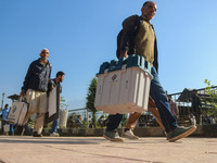 Polling officials carry electronic voting machines (EVM) at a distribution center in Sumbal area of Bandipora district, North of Srinagar, o...