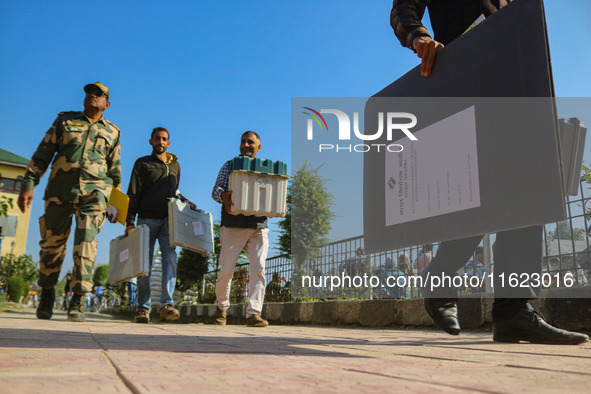 Polling officials carry electronic voting machines (EVM) at a distribution center in Sumbal area of Bandipora district, North of Srinagar, o...