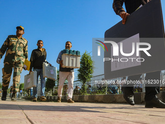 Polling officials carry electronic voting machines (EVM) at a distribution center in Sumbal area of Bandipora district, North of Srinagar, o...