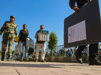 Polling officials carry electronic voting machines (EVM) at a distribution center in Sumbal area of Bandipora district, North of Srinagar, o...