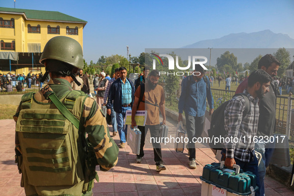 An Indian paramilitary soldier stands guard as polling officials carry electronic voting machines (EVM) at a distribution center in the Sumb...