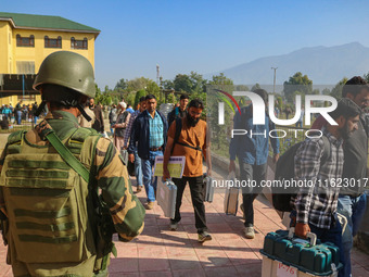 An Indian paramilitary soldier stands guard as polling officials carry electronic voting machines (EVM) at a distribution center in the Sumb...