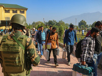 An Indian paramilitary soldier stands guard as polling officials carry electronic voting machines (EVM) at a distribution center in the Sumb...