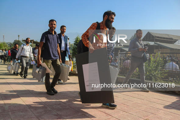 Polling officials carry electronic voting machines (EVM) at a distribution center in Sumbal area of Bandipora district, North of Srinagar, o...