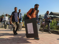 Polling officials carry electronic voting machines (EVM) at a distribution center in Sumbal area of Bandipora district, North of Srinagar, o...