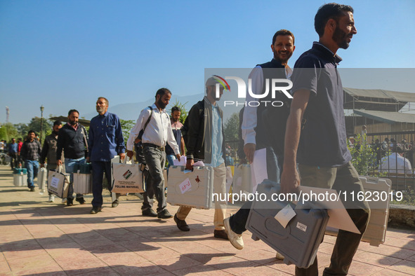 Polling officials carry electronic voting machines (EVM) at a distribution center in Sumbal area of Bandipora district, North of Srinagar, o...