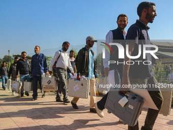 Polling officials carry electronic voting machines (EVM) at a distribution center in Sumbal area of Bandipora district, North of Srinagar, o...