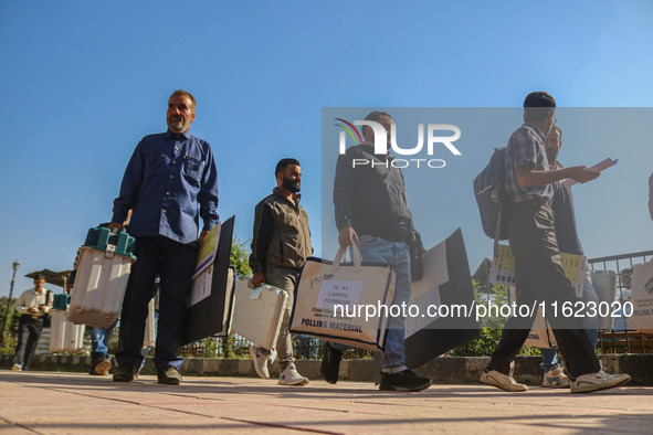 Polling officials carry electronic voting machines (EVM) at a distribution center in Sumbal area of Bandipora district, North of Srinagar, o...