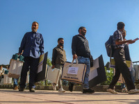 Polling officials carry electronic voting machines (EVM) at a distribution center in Sumbal area of Bandipora district, North of Srinagar, o...