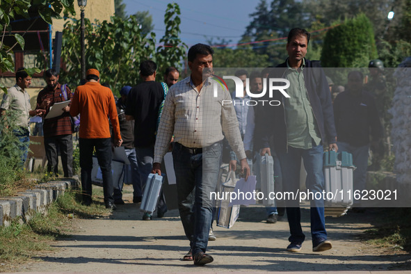 Polling officials carry electronic voting machines (EVM) at a distribution center in Sumbal area of Bandipora district, North of Srinagar, o...