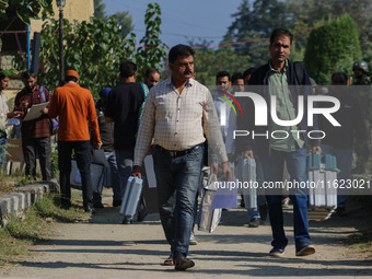 Polling officials carry electronic voting machines (EVM) at a distribution center in Sumbal area of Bandipora district, North of Srinagar, o...