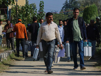 Polling officials carry electronic voting machines (EVM) at a distribution center in Sumbal area of Bandipora district, North of Srinagar, o...