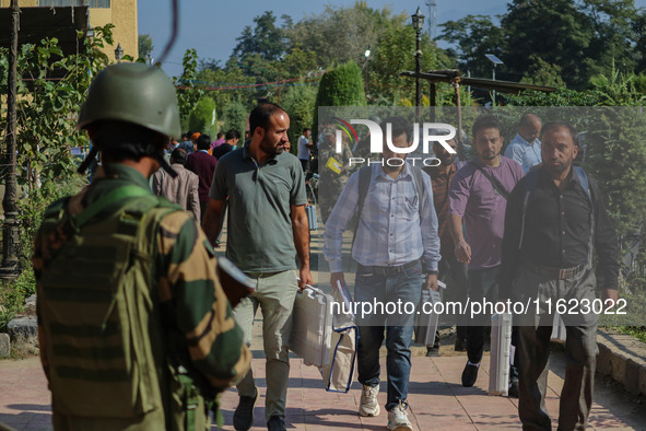 An Indian paramilitary soldier stands guard as polling officials carry electronic voting machines (EVM) at a distribution center in the Sumb...