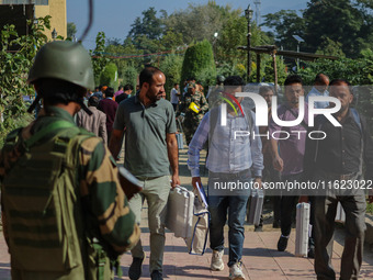 An Indian paramilitary soldier stands guard as polling officials carry electronic voting machines (EVM) at a distribution center in the Sumb...