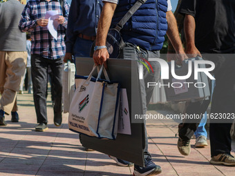 Polling officials carry electronic voting machines (EVM) at a distribution center in Sumbal area of Bandipora district, North of Srinagar, o...