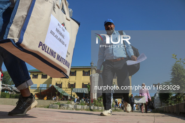 Polling officials carry electronic voting machines (EVM) at a distribution center in Sumbal area of Bandipora district, North of Srinagar, o...