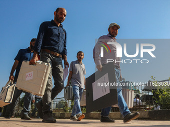 Polling officials carry electronic voting machines (EVM) at a distribution center in Sumbal area of Bandipora district, North of Srinagar, o...