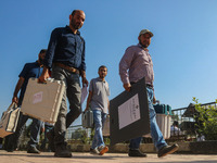 Polling officials carry electronic voting machines (EVM) at a distribution center in Sumbal area of Bandipora district, North of Srinagar, o...