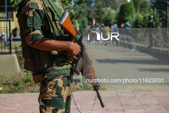 An Indian paramilitary soldier stands guard as polling officials carry electronic voting machines (EVM) at a distribution center in the Sumb...