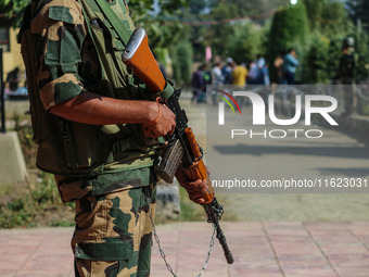 An Indian paramilitary soldier stands guard as polling officials carry electronic voting machines (EVM) at a distribution center in the Sumb...