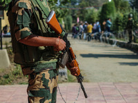 An Indian paramilitary soldier stands guard as polling officials carry electronic voting machines (EVM) at a distribution center in the Sumb...