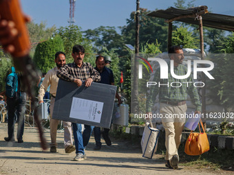 An Indian paramilitary soldier stands guard as polling officials carry electronic voting machines (EVM) at a distribution center in the Sumb...