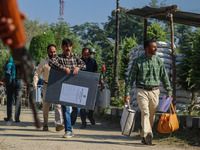 An Indian paramilitary soldier stands guard as polling officials carry electronic voting machines (EVM) at a distribution center in the Sumb...