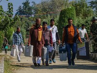 Polling officials carry electronic voting machines (EVM) at a distribution center in Sumbal area of Bandipora district, North of Srinagar, o...