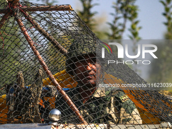 An Indian paramilitary soldier stands guard as polling officials carry electronic voting machines (EVM) at a distribution center in the Sumb...