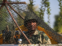 An Indian paramilitary soldier stands guard as polling officials carry electronic voting machines (EVM) at a distribution center in the Sumb...