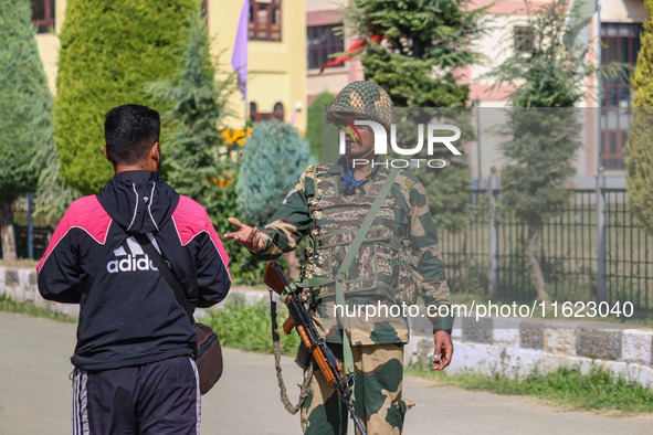 An Indian paramilitary soldier questions a man as polling officials carry electronic voting machines (EVM) at a distribution center in Sumba...