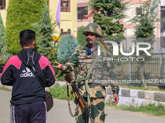 An Indian paramilitary soldier questions a man as polling officials carry electronic voting machines (EVM) at a distribution center in Sumba...