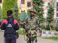 An Indian paramilitary soldier questions a man as polling officials carry electronic voting machines (EVM) at a distribution center in Sumba...