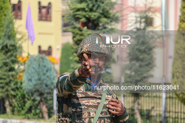 An Indian paramilitary soldier stands guard as polling officials carry electronic voting machines (EVM) at a distribution center in the Sumb...