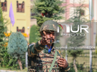 An Indian paramilitary soldier stands guard as polling officials carry electronic voting machines (EVM) at a distribution center in the Sumb...