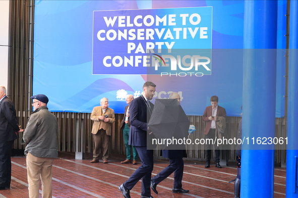 Delegates arrive in the pouring rain to the Conservative Party Conference at the International Conference Centre in Birmingham, United Kingd...