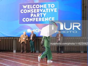 Delegates arrive in the pouring rain to the Conservative Party Conference at the International Conference Centre in Birmingham, United Kingd...