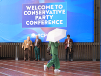 Delegates arrive in the pouring rain to the Conservative Party Conference at the International Conference Centre in Birmingham, United Kingd...