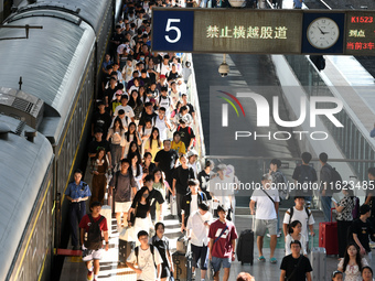 Passengers get on and off a train at Nanchang Railway Station in Nanchang, China, on September 30, 2024. (