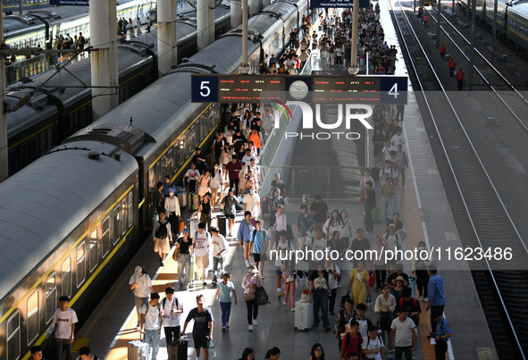 Passengers get on and off a train at Nanchang Railway Station in Nanchang, China, on September 30, 2024. 