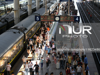 Passengers get on and off a train at Nanchang Railway Station in Nanchang, China, on September 30, 2024. (