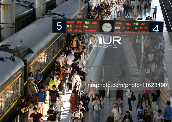 Passengers get on and off a train at Nanchang Railway Station in Nanchang, China, on September 30, 2024. 